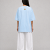 Back of TAP light blue oversized tee with gold paw logo on the upper back, female model