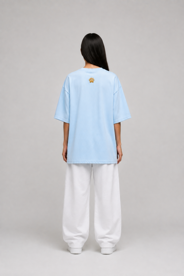 Back of TAP light blue oversized tee with gold paw logo on the upper back, female model